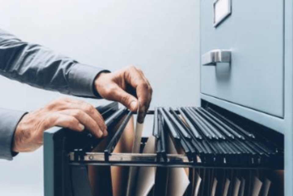 Simbolna slika osebe, ki brska po omari z dokumenti