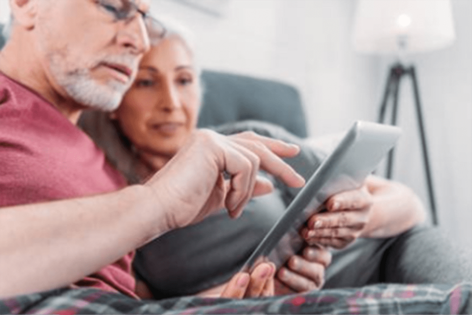 Simbolna slika starejšega para, ki držita tablico v roki in gledata vanjo