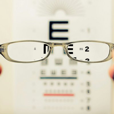 Simbolna fotografija očal, v ozadju tabla s črkami in številkami