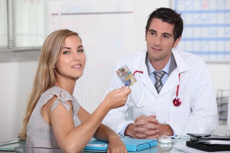 Symbolic photo of a doctor and a patient holding the Slovene Health Insurance Card