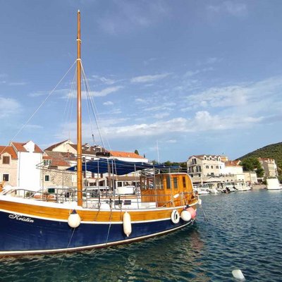 Simbolna fotografija parkirane jadrnice, vidno morje in hiše v ozadju