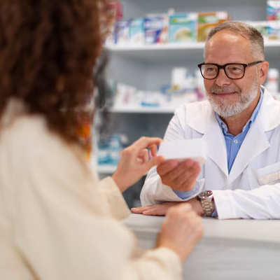 Simbolna fotografija farmacevta v lekarni, ki predaja stranki zdravilo