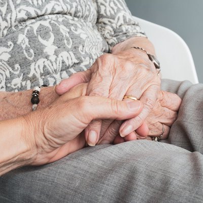 Simbolna slika pomoči kot držanja za roke med starejšo in mlajšo osebo