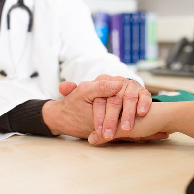 Simbolična fotografija stisnjenih rok zdravnika in pacienta