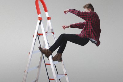 Simbolna fotografija moškega, ki pada z lestve