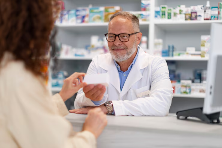 Simbolna fotografija farmacevta v lekarni, ki predaja stranki zdravilo